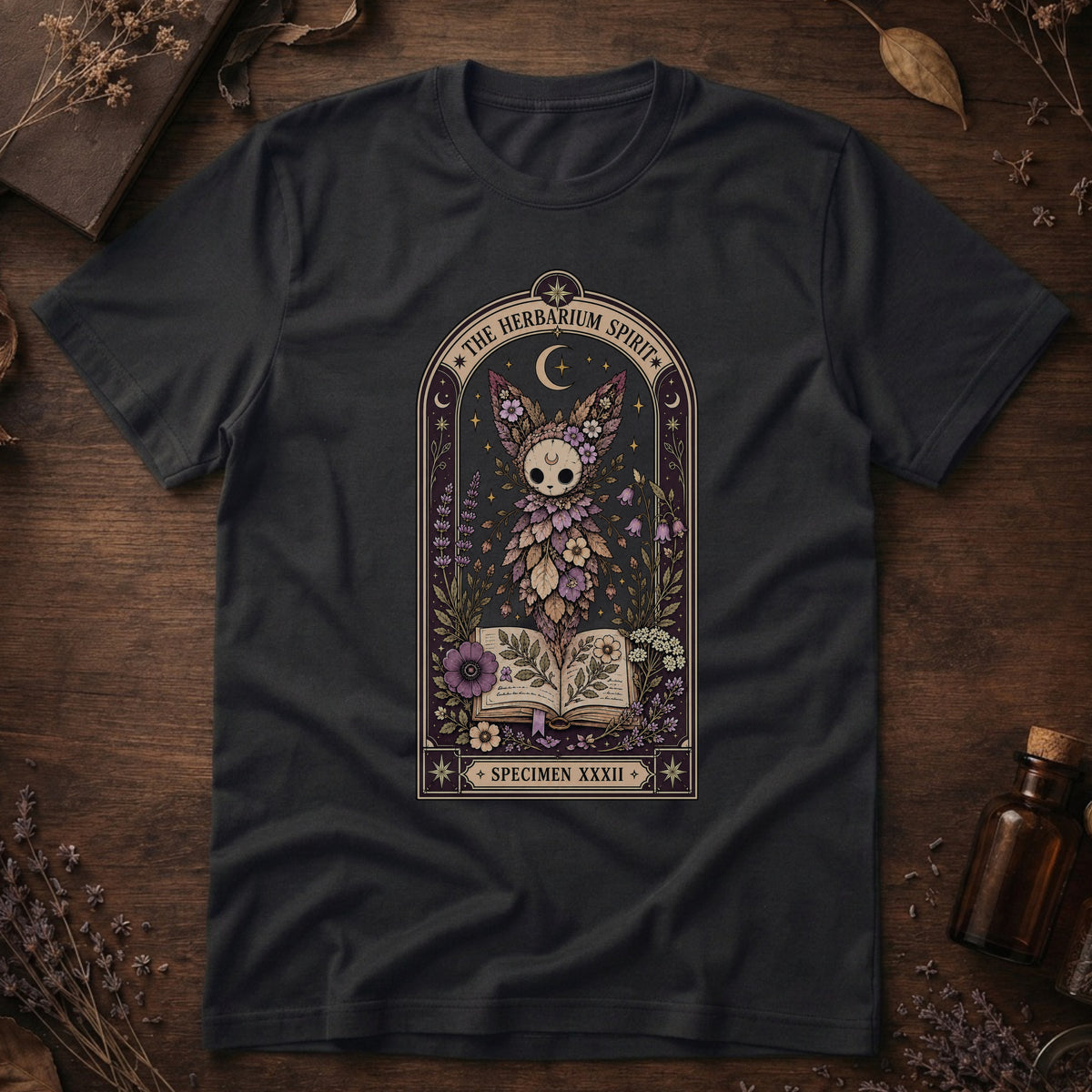 Vintage black t-shirt with a gothic herbarium illustration: a skull-shaped plant sprouting purple and pink flowers above an open botanical book, framed in an arch with a crescent moon.
