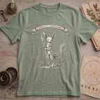 Sage green t-shirt with a vintage illustration of a winged rabbit-like frost spirit holding a spear, surrounded by botanical linework and a Specimen No. 31 banner.