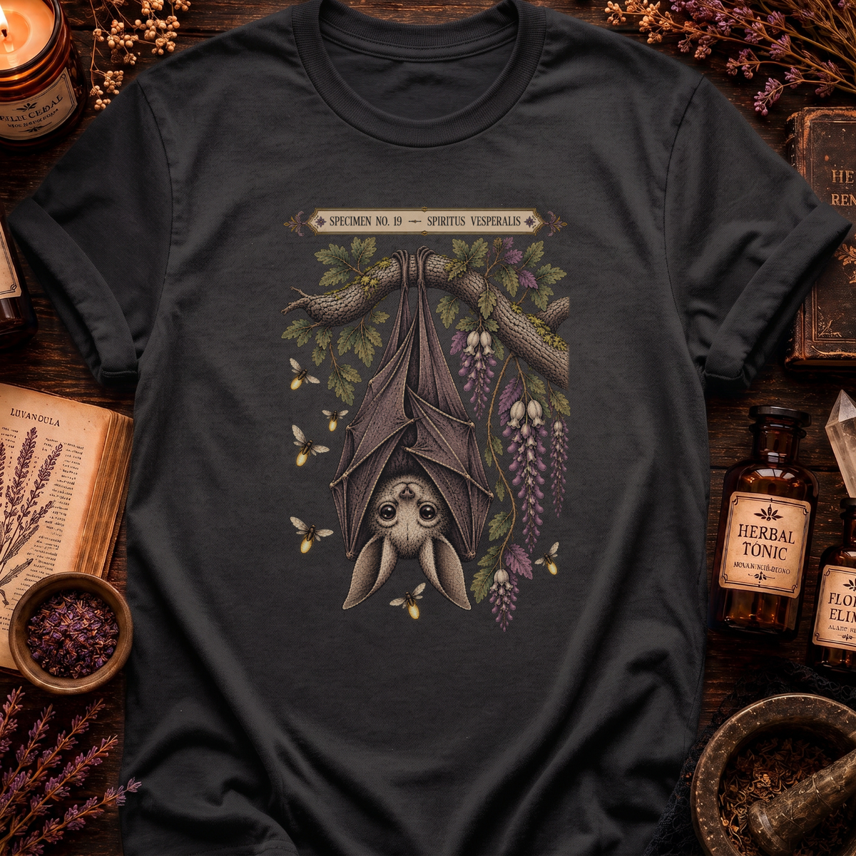 Asphalt grey t-shirt with a botanical illustration of a hanging bat spirit among wisteria blossoms and bees, framed by a Specimen No. 19 banner.