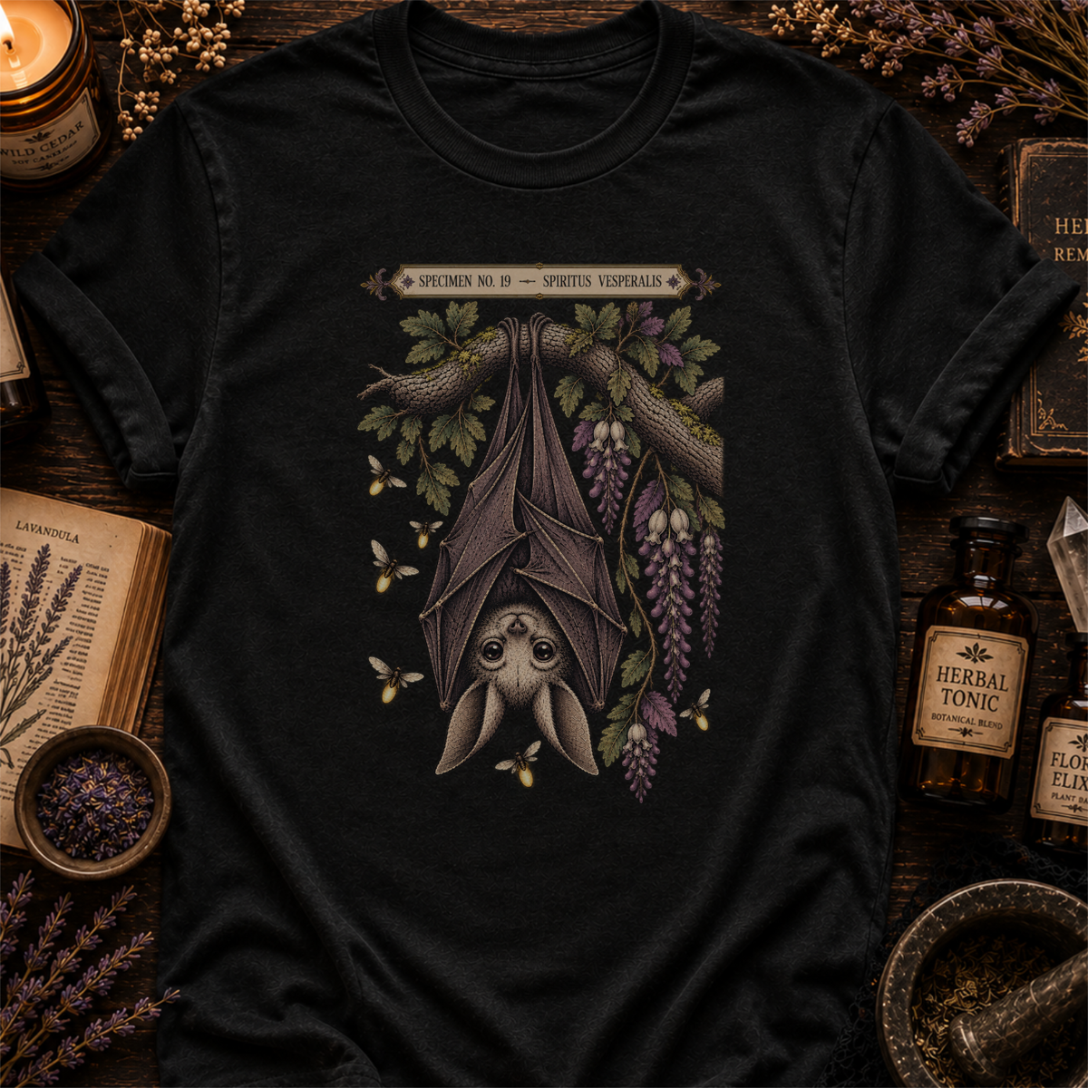 Black t-shirt with a botanical illustration of a hanging bat spirit among wisteria blossoms and bees, framed by a Specimen No. 19 banner.
