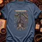 Steel blue t-shirt with a botanical illustration of a hanging bat spirit among wisteria blossoms and bees, framed by a Specimen No. 19 banner.