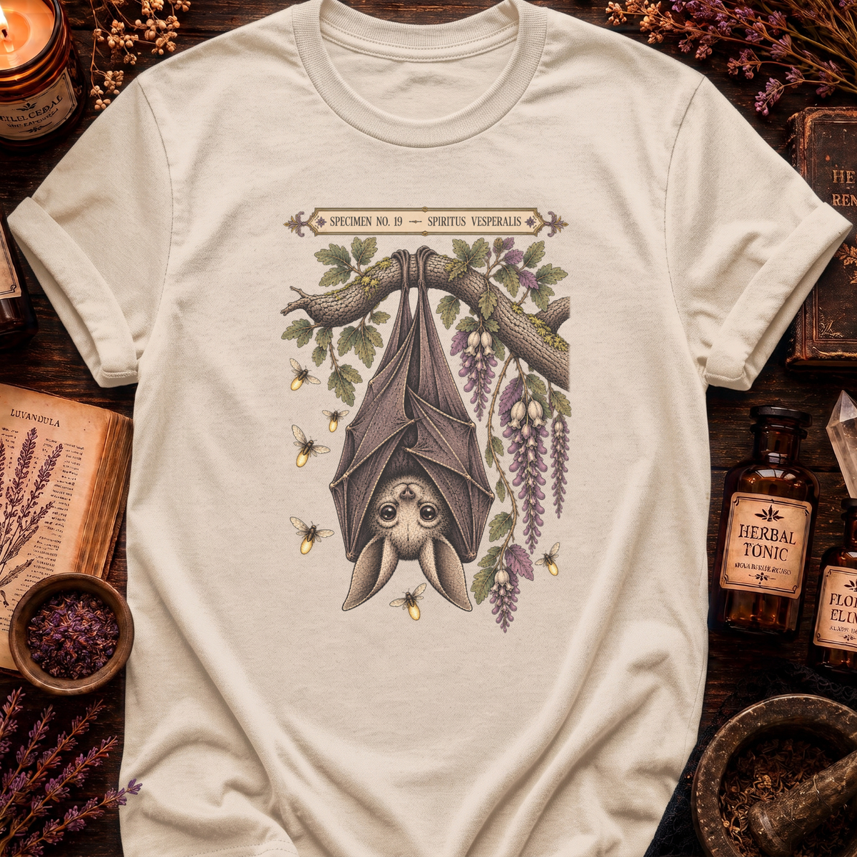 Cream t-shirt with a botanical illustration of a hanging bat spirit among wisteria blossoms and bees, framed by a Specimen No. 19 banner.