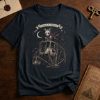 Black t-shirt with a gothic illustration of a skeletal cat spirit with a flowing scarf riding an old mechanical ferris wheel beneath a crescent moon.