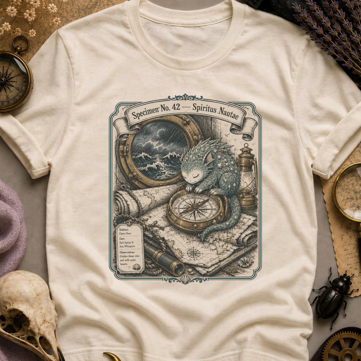 Vintage white t-shirt with a sepia-toned illustration of a sea spirit resting a paw on a brass compass atop an antique nautical map, with a stormy porthole scene above.